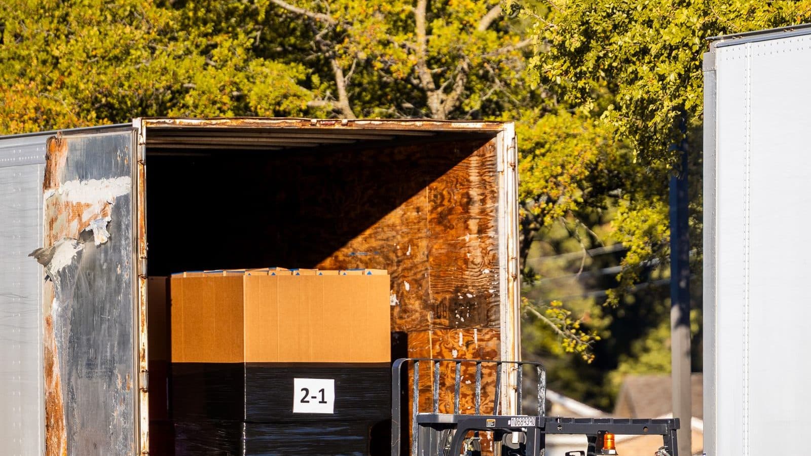 An open trailer with a box inside and a forklift at the door