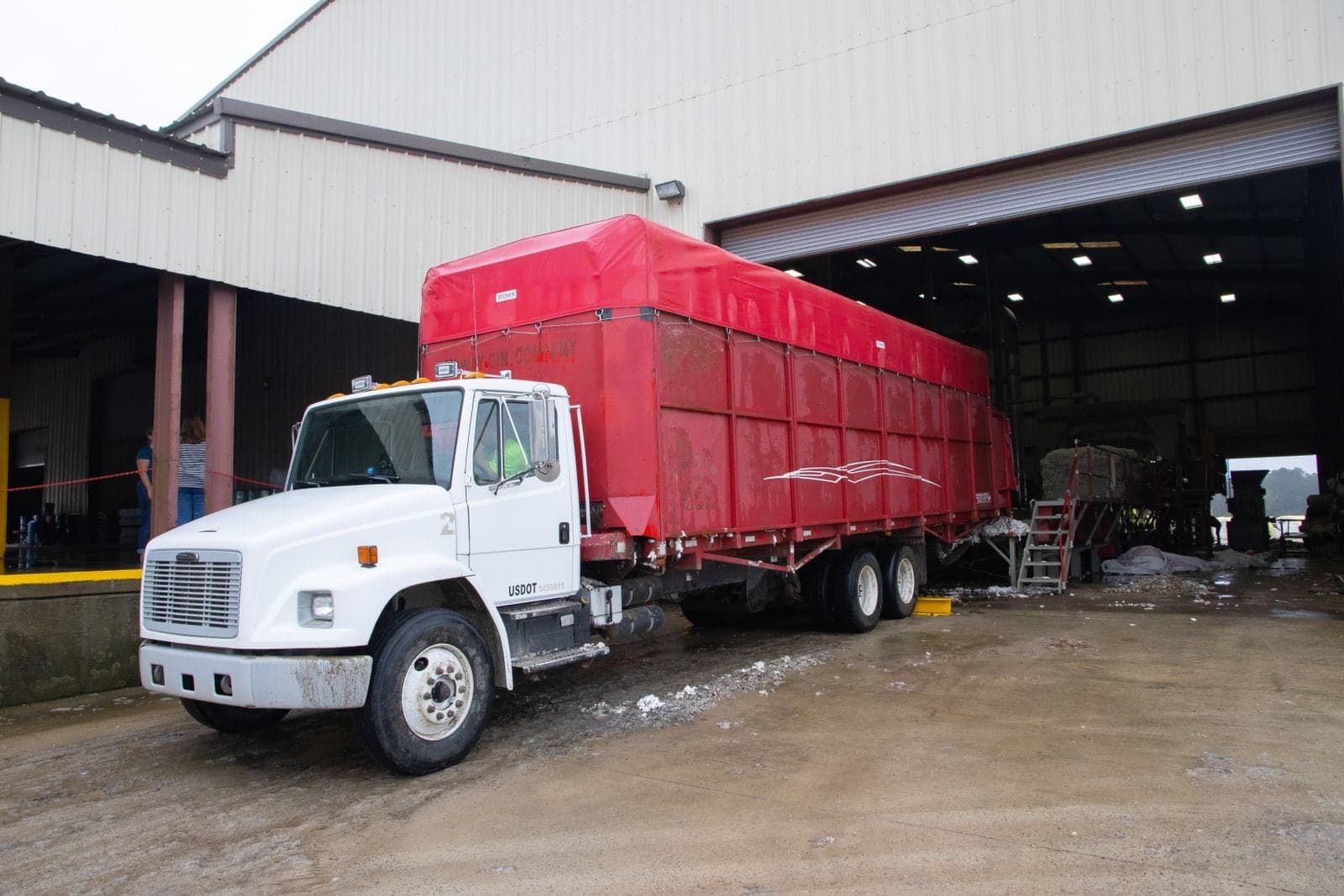 A white tractor and red trailer at a warehouse door