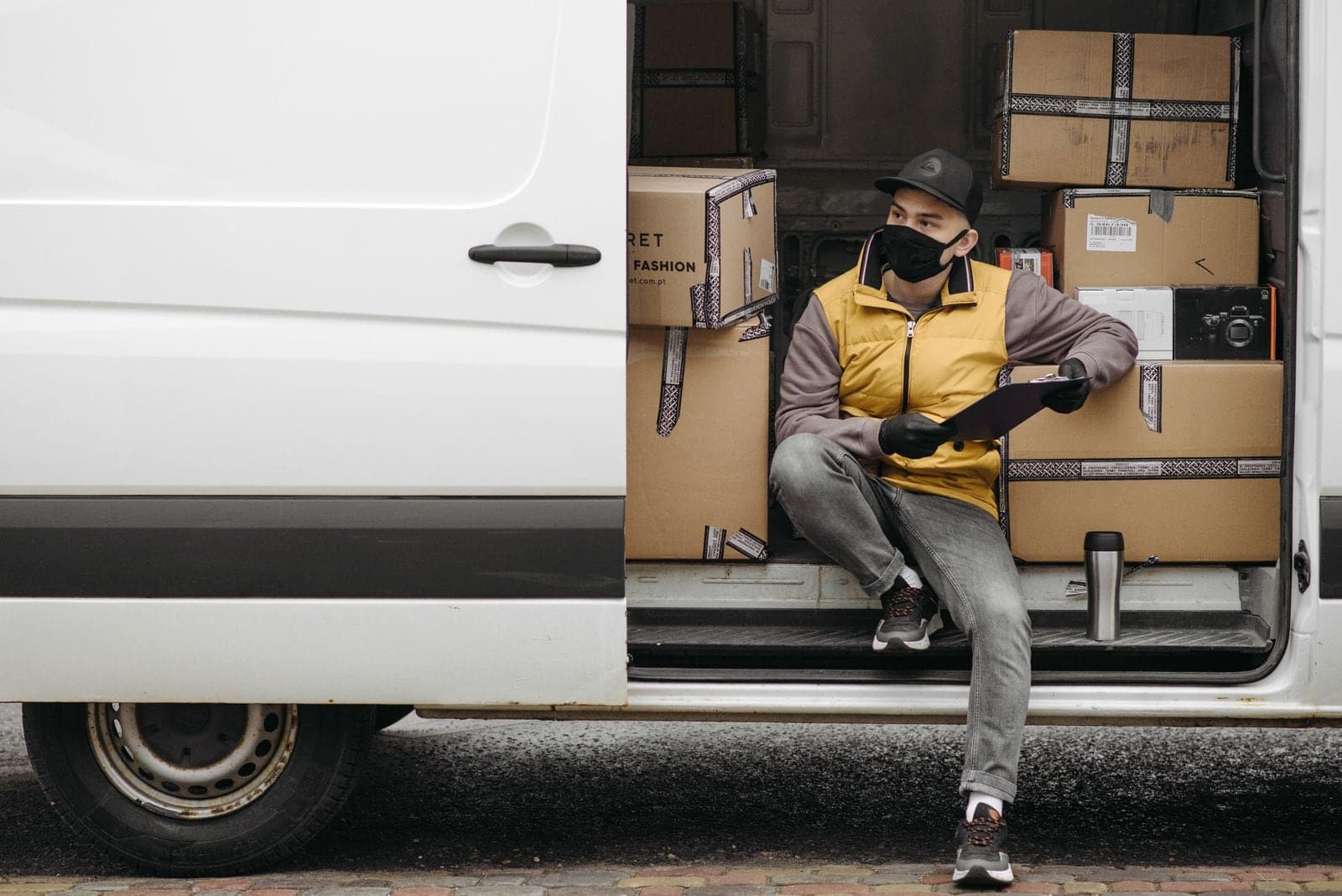 A driver with a clipboard at the open back of a van